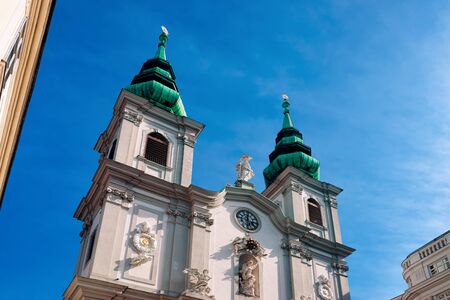 Two towers of Church of Mariahilf on Mariahilfer Strasse Street in Vienna in Austria. Cathedral archtecture in Wien. Basilica Building landmark. Austrian town. Blue sky backgroundの写真素材