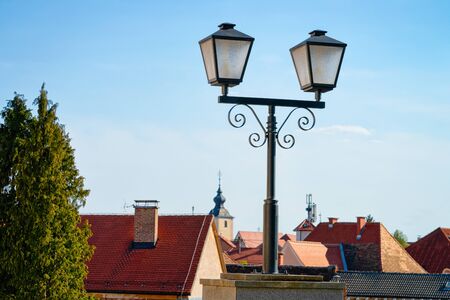 Cityscape with street lantern and house roofs with Our Lady of the Seven Sorrows Church in Old center in Slovenska Bistrica near Maribor in Slovenia. South Styria in Slovenija. Light in Slovenian townの写真素材