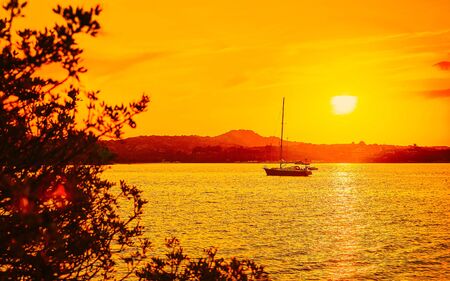 Sunrise or sunset with yachts at Porto Rotondo on Costa Smeralda at Mediterranean sea in Sardinia island of Italy. Boat in Sardegna in summer. Landscape of Olbia province. Mixed media.の写真素材