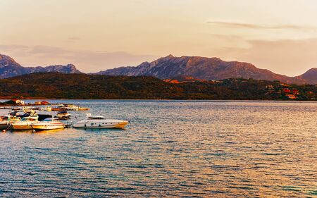 Sunrise or sunset with yachts at Porto Rotondo at the Mediterranean sea in Sardinia island of Italy. Boat in Sardegna in summer. Landscape of Olbia province. Mixed media.の写真素材