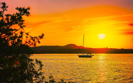 Sunrise or sunset with yachts at Porto Rotondo at the Mediterranean sea in Sardinia island of Italy. Boat in Sardegna in summer. Landscape of Olbia province. Mixed media.の写真素材