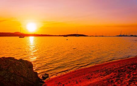 Sunrise or sunset with yachts at Porto Rotondo at the Mediterranean sea in Sardinia island of Italy. Boat in Sardegna in summer. Landscape of Olbia province. Mixed media.の写真素材