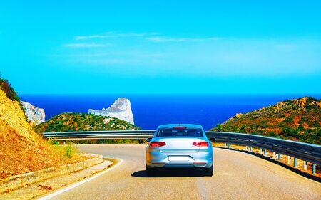 Car on road at Porto Corallo Nebida Mediterranean Sea Sardinia reflexの写真素材