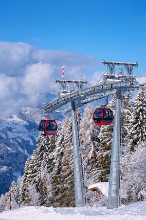 Red Cable cars at Zillertal Arena ski resort in Tyrol in Mayrhofen in Austria in winter Alps. Chair lifts in Alpine mountains with white snow and blue sky. Downhill fun at Austrian snowy slopes.の写真素材