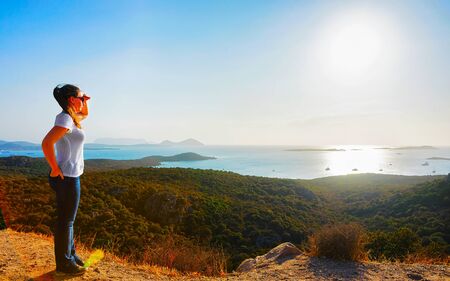 Scenery with girl at Porto Rotondo at sunrise or sunset at the Mediterranean Sea. Woman and Porto Cervo in Sardinia Island in Italy in summer. Landscape of Olbia province. Mixed media.の写真素材