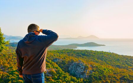 Scenery with man at Porto Rotondo at sunrise or sunset at the Mediterranean Sea. Porto Cervo in Sardinia Island in Italy in summer. Landscape of Olbia province. Mixed media.の写真素材