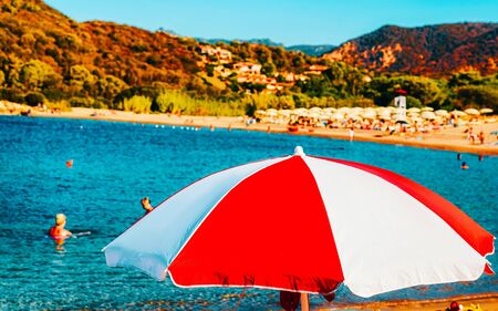 Landscape of Chia Beach with umbrellas and Blue Waters of the Mediterranean Sea in Province of Cagliari in South Sardinia in Italy. Scenery and nature. Mixed media.の写真素材