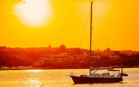Sunrise or sunset with yachts at Porto Rotondo at the Mediterranean sea in Sardinia island of Italy. Boat in Sardegna in summer. Landscape of Olbia province. Mixed media.の写真素材