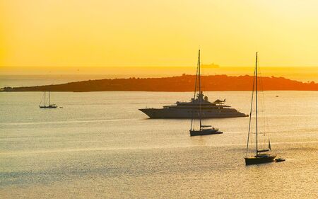 Sunrise or sunset with yachts at Porto Rotondo at Mediterranean sea in Sardinia island of Italy. Boat in Sardegna in summer. Landscape of Olbia province. Mixed media.の写真素材