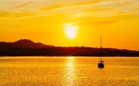 Sunrise or sunset with yachts at Porto Rotondo on Costa Smeralda at Mediterranean sea in Sardinia island of Italy. Boat in Sardegna in summer. Landscape of Olbia province. Mixed media.の写真素材