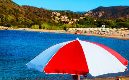 Landscape of Chia Beach with umbrellas and Blue Waters of the Mediterranean Sea in Province of Cagliari in South Sardinia in Italy. Scenery and nature. Mixed media.の写真素材