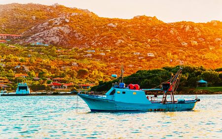 Sunrise or sunset with yachts at Porto Rotondo on Costa Smeralda at Mediterranean sea in Sardinia island of Italy. Boat in Sardegna in summer. Landscape of Olbia province. Mixed media.の写真素材