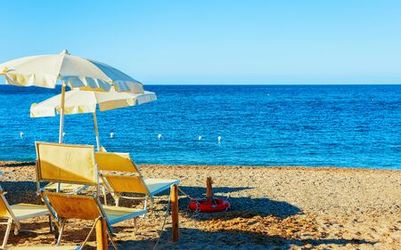 Landscape of Chia Beach with umbrellas and Blue Waters of the Mediterranean Sea in Province of Cagliari in South Sardinia in Italy. Scenery and nature. Mixed media.の写真素材