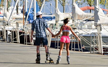 Lausanne, Switzerland - August 26, 2016: Young couple roller skating at the embankment of Marina on Lake Geneva, Lausanne, Ouchy fishing village, Switzerland. Mixed media.のeditorial素材