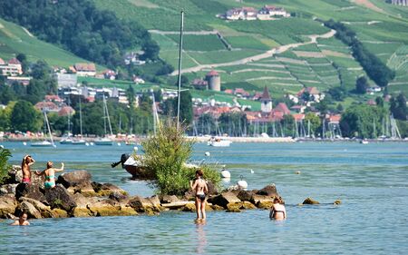 People swimming and sunbathing at Lakefront of Lake Geneva, Lausanne, Switzerland. Mixed media.の写真素材