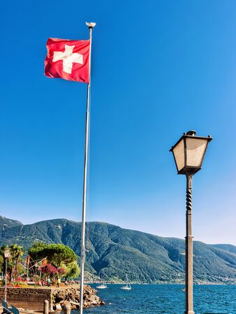Swiss flag at the luxurious resort in Ascona on Lake Maggiore in Ticino canton in Switzerland. Mixed media.の写真素材