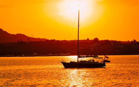 Sunrise or sunset with yachts at Porto Rotondo at the Mediterranean sea in Sardinia island of Italy. Boat in Sardegna in summer. Landscape of Olbia province. Mixed media.の写真素材