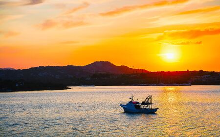 Sunrise or sunset with yachts at Porto Rotondo on Costa Smeralda at Mediterranean sea in Sardinia island of Italy. Boat in Sardegna in summer. Landscape of Olbia province. Mixed media.の写真素材