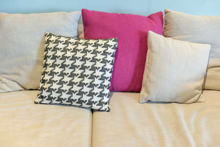 pink and plaid pillows on beige sofa