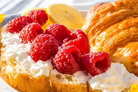 croissants with raspberries and whipped cream for breakfastの写真素材