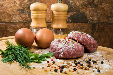 Meat cutlets prepared for cooking with spices and herbsの写真素材