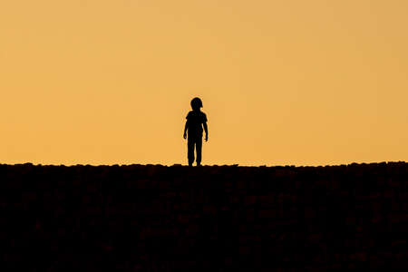 A kid standing on Kizkalesi castle while sunsetの写真素材