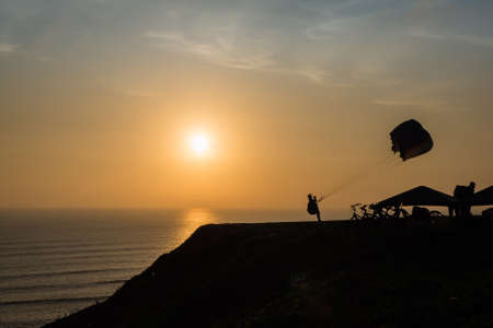 Sunset in the cliffs of Lima city in Peru, with a man doing paraglidingの写真素材
