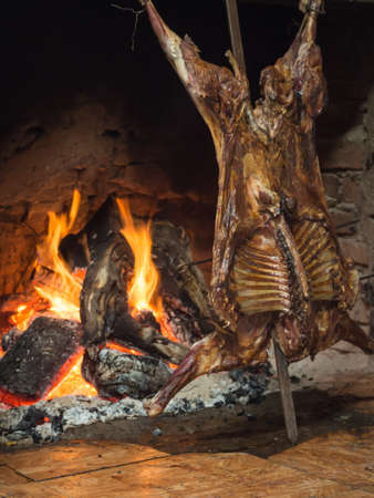 Patagonian roast lamb, tipical dish of Chile and Argentina,  cooked very slowly over the embers of hot burning hard woodの写真素材