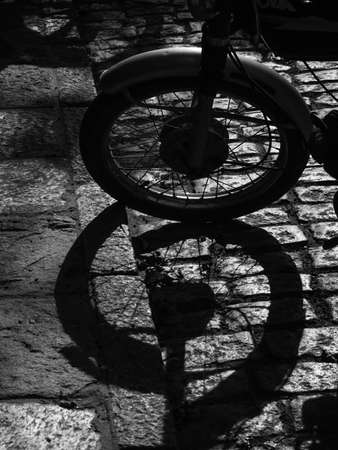 Detail of the wheel of a motorbike and his shadow. Black and white photography