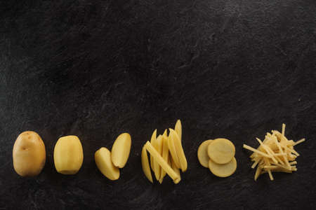 Different cuts of potatoes on a black textured background. Photo taken from aboveの写真素材