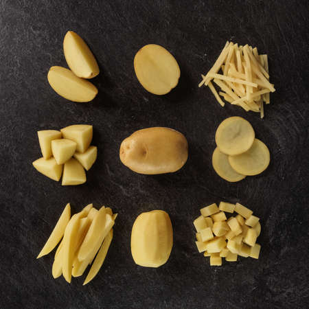 Different cuts of potatoes on a black textured background. Photo taken from aboveの写真素材
