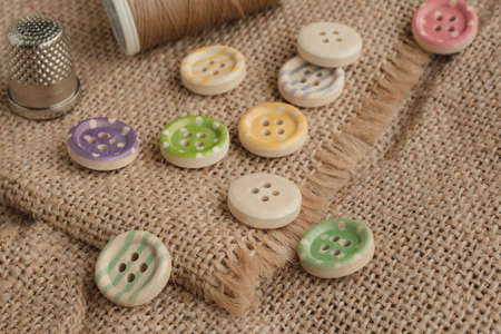 Wooden buttons with stripes of colored colors on a rustic fabric, sewing