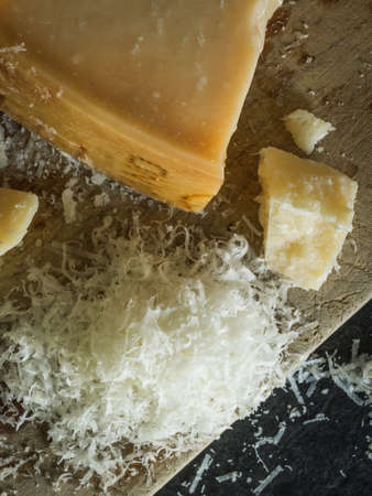 Grated parmesan cheese on black background, italian food. Dark food