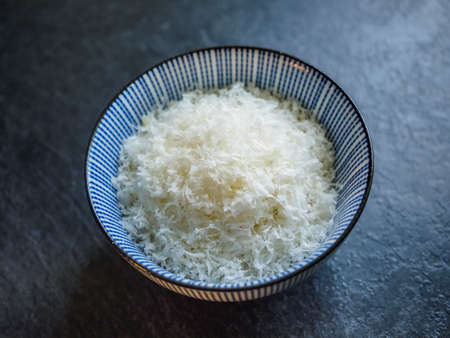 Grated parmesan cheese in a bowl on black background, italian food. Dark foodの写真素材