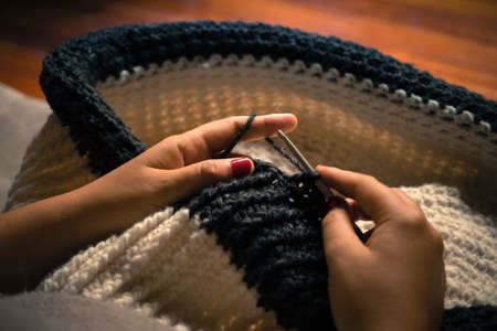 Girl making a crochet puff with white and gray wool and nails painted red close up photography, handcraftsの写真素材