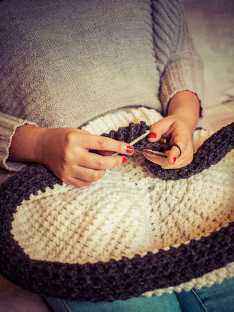 Girl making a crochet puff with white and gray wool and nails painted red close up photography,...