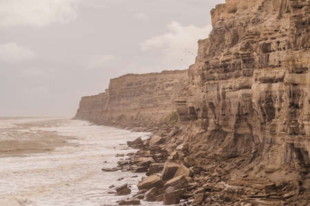 Cliffs in La Loberia, Argenina. Cloudy day with waves. Biggest canyon parrots colony in the worldの写真素材