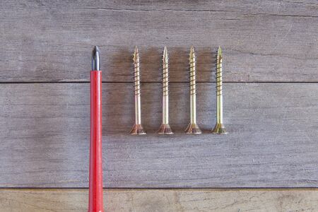 screwdriver and a lot of screws on a piece of woodの写真素材