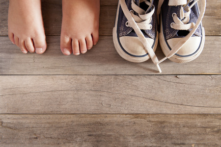 Picture of a child shoe and feet on a wooden floorの写真素材
