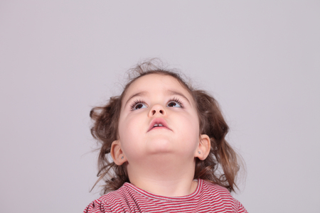Cute little girl looking up against of white background.Studio shot. Isolatedの写真素材
