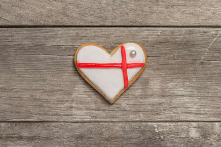 Baked valentine's heart covered with white and red icing. wooden background, from aboveの写真素材