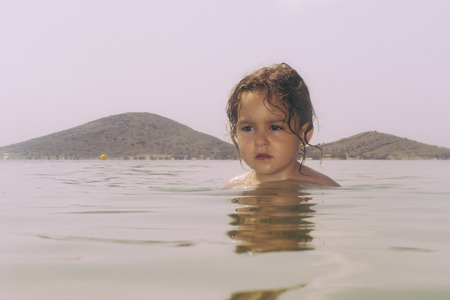 Headshot of little girl in water against of mountainsの写真素材