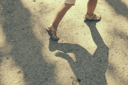 Little girl's legs in sandals running on ground.の写真素材