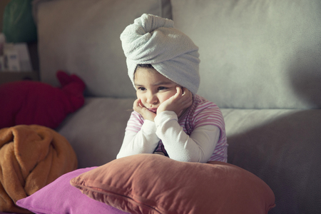 Close-up of little upset girl leaning her head on hands while looking awayの写真素材