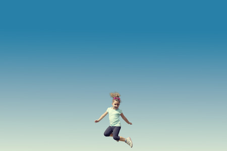 A little kid jumps into the sky. Horizontal outdoors shotの写真素材