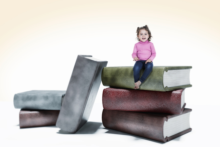Smiling little girls sits on huge books.の写真素材
