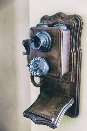 Vintage wooden phone hanging on a wall. Vertical indoors shotの写真素材