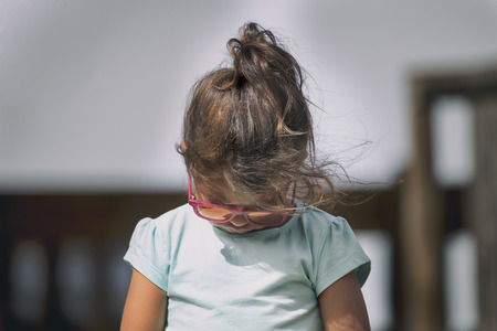 Horizontal shot of cute little child wearing sunglasses looking down.