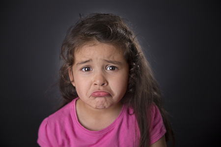 Portrait of a sad four years girl in black background. Studio shot