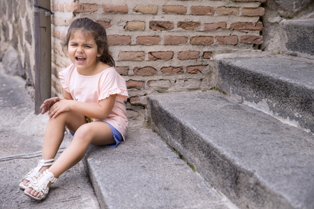 Portrait of offended four years girl sitting on a stairsの写真素材